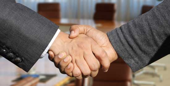 Close up on the hands of two men in business suite shaking hands.  Both have clean hands, and one of the hands has darker skin.